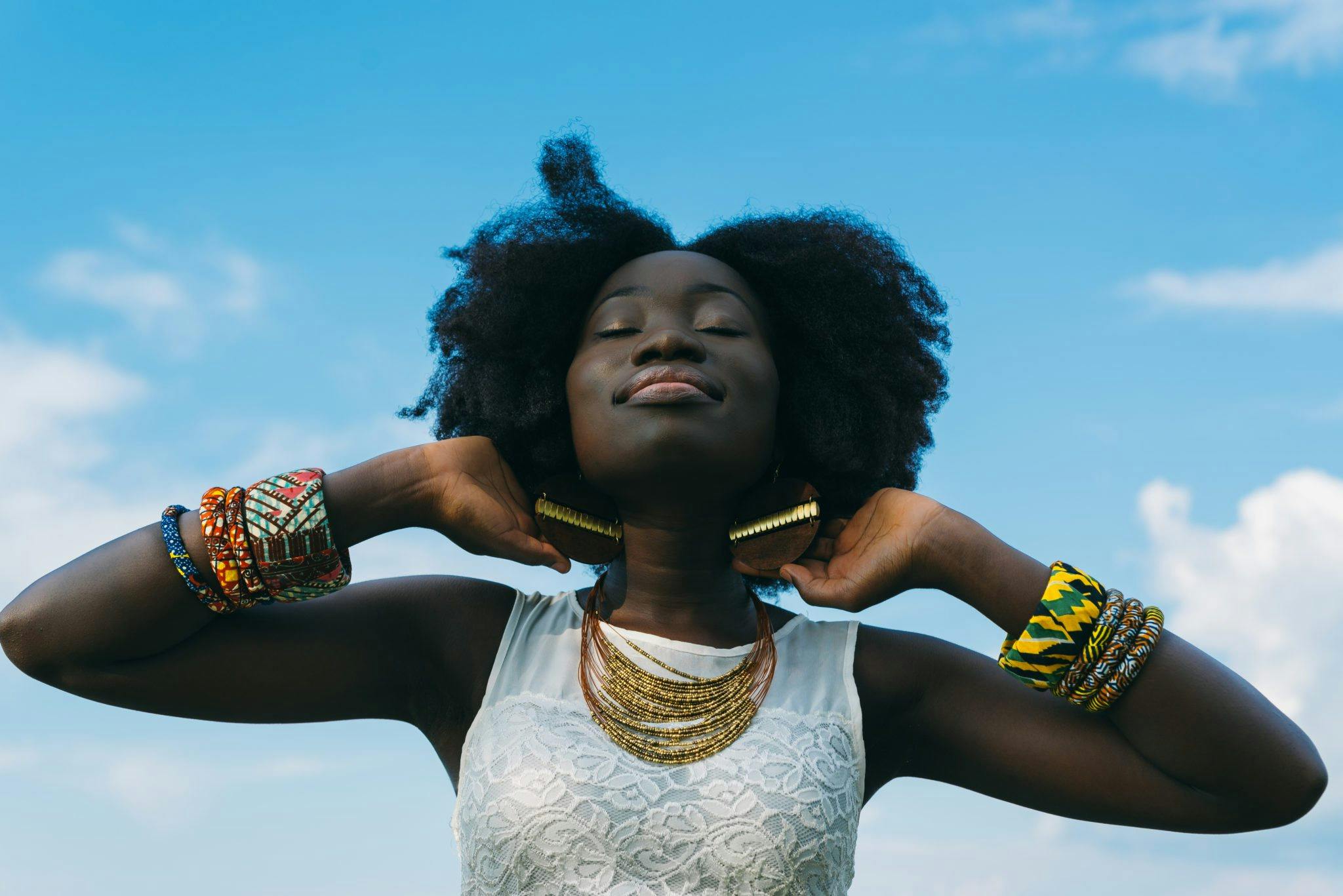 Woman smiling with her eyes closed adorned in African-inspired jewellery